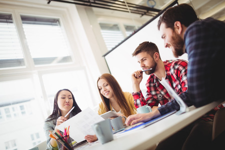 Tilt image of photo editors discussing about document in meeting room at officeの写真素材