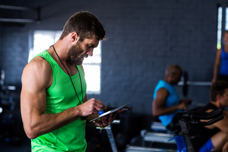 Hipster man using tablet while standing in gymの写真素材