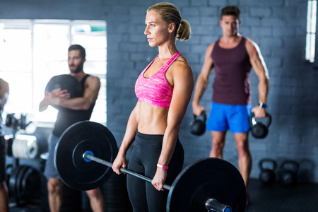 Female athlete holding barbell in gymの写真素材