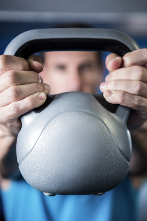Man holding kettlebell in gymの写真素材