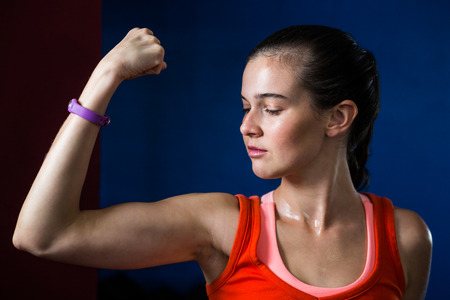 Close-up of woman flexing muscles while standing in gymの写真素材