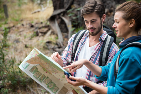 Hiker couple looking at map in forestの写真素材