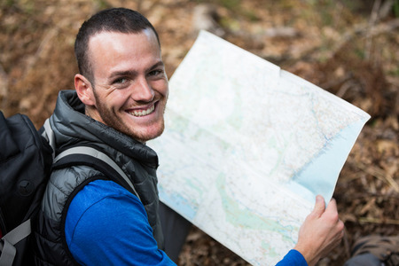 Portrait of smiling male hiker holding a map in forestの写真素材