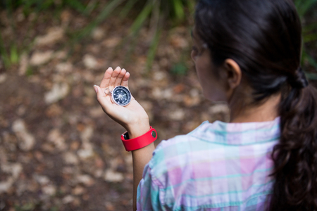 Female hiker looking at compass in forestの写真素材