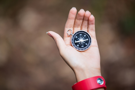 Close-up of hand holding compass in forestの写真素材