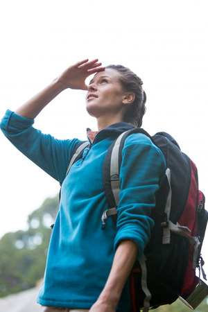 Female hiker shielding her eyes in forestの写真素材