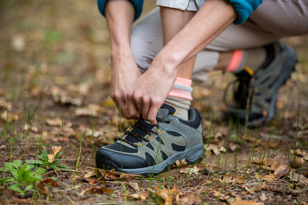 Female hiker tying shoelaces outdoors in forestの写真素材