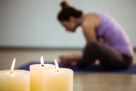 Close-up of three lit candles and blurred woman exercising in backgroundの写真素材