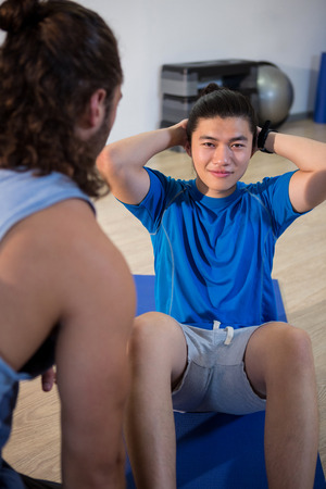 Fitness man talking to instructor in gymの写真素材
