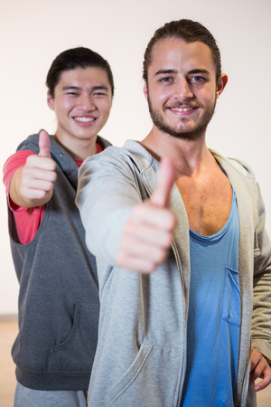Portrait of happy men showing thumbs up in gymの写真素材