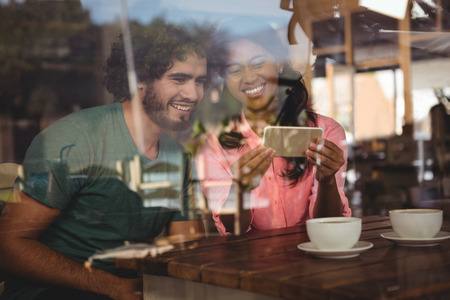 Couple looking at mobile phone in cafeteriaの写真素材