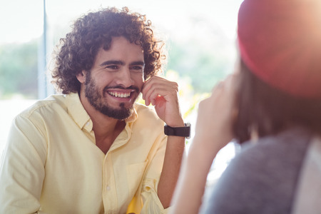 Smiling couple interacting with each other in cafeの写真素材