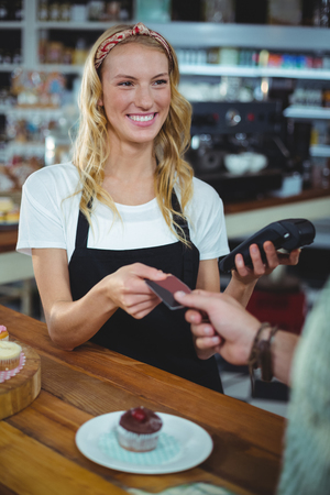 Customer giving credit card to waitress in cafÃ©の写真素材