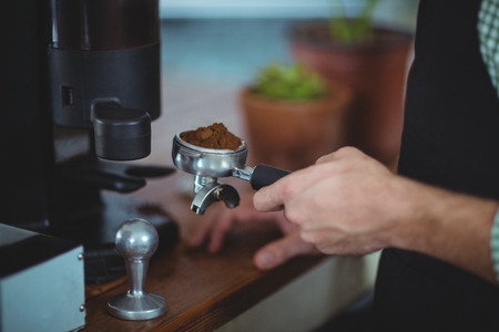 Waiter holding portafilter filled with ground coffee in cafeの写真素材