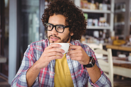 Thoughtful man having coffee in cafeteriaの写真素材