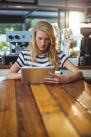 Thoughtful woman sitting in a cafe using digital tabletの写真素材