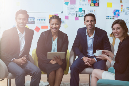 Portrait of businesspeople sitting in front of whiteboard in the office