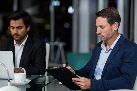 Businessman writing on clipboard in the officeの写真素材
