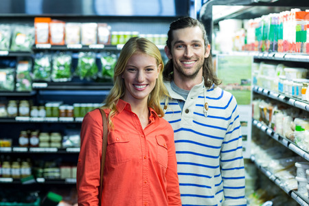Portrait of happy couple standing in supermarketの写真素材
