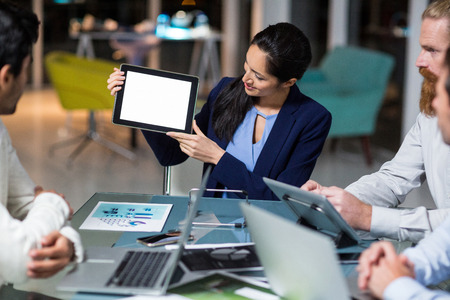 Businesswoman showing digital tablet to colleagues in the officeの写真素材