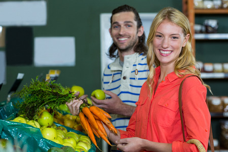 Happy couple selecting fruits and carrots in organic section of supermarketの写真素材