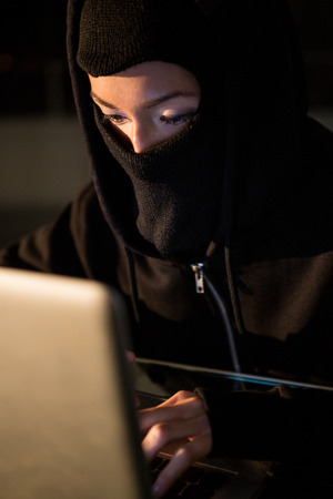 Close-up of woman in balaclava using laptop in the officeの写真素材