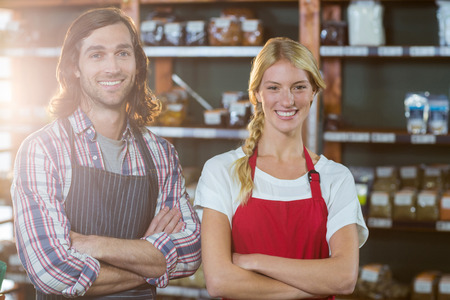 Portrait of smiling staffs standing with arms crossed in supermarketの写真素材