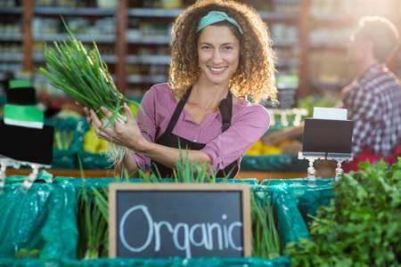 Portrait of smiling staff holding vegetable in organic section of supermarketの写真素材