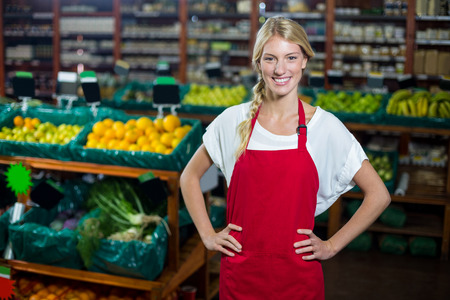 Portrait of smiling staff standing with hand on hip in organic section of supermarketの写真素材