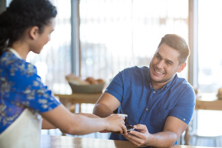 Waitress serving a cup of coffee to customer in cafeの写真素材