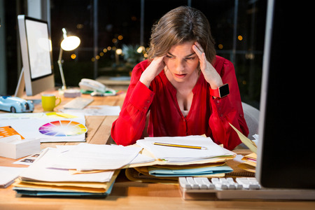 Stressed businesswoman sitting in front of computer in the officeの写真素材