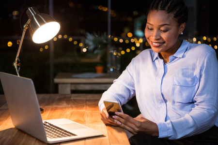 Businesswoman using mobile phone at her desk in the officeの写真素材