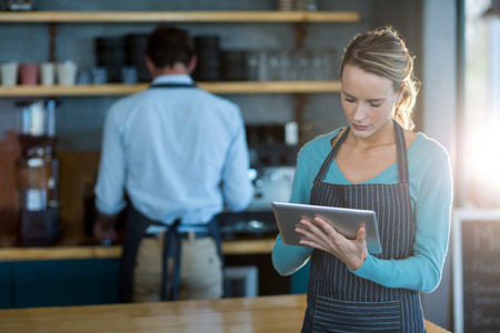 Waitress using digital tablet at counter in cafÃ©の写真素材
