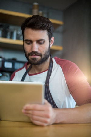 Waiter using digital tablet at counter in cafÃ©の写真素材