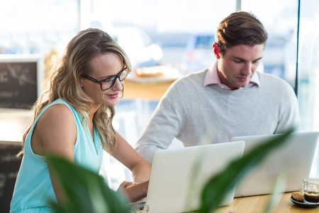 Man and woman using laptop during meeting in cafeの写真素材