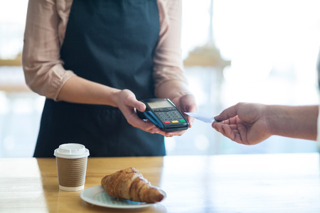 Man paying bill through payment terminal in cafe