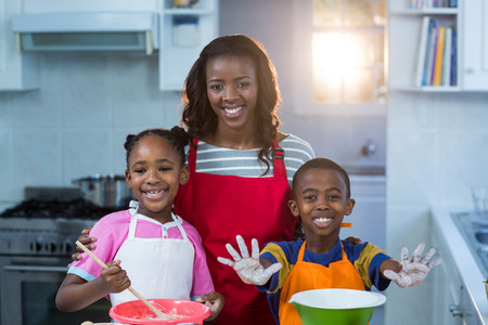 Children preparing cake with their mother in kitchenの写真素材