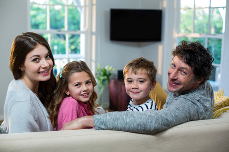 Portrait of family sitting on sofa at homeの写真素材