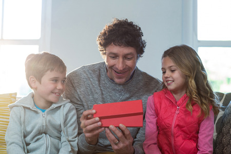 Father opening gift box with children at homeの写真素材