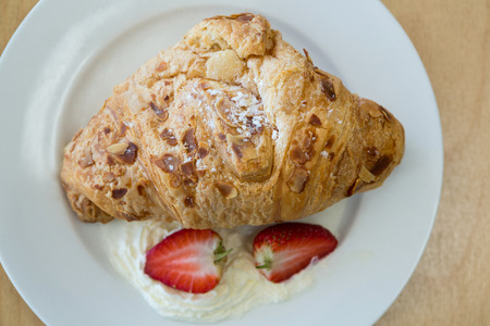 Close-up of croissant and strawberry on plate in cafeteriaの写真素材