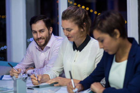 Businesspeople preparing document in office at nightの写真素材