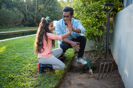 Father and daughter planting tree in garden at backyardの写真素材