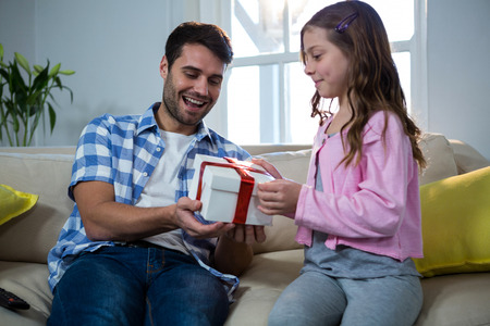 Father giving gift to daughter in the living room at homeの写真素材