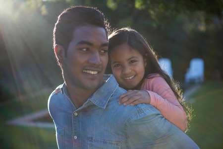 Father giving piggyback ride to his daughter in the gardenの写真素材