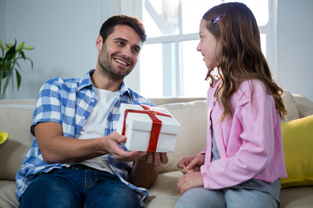 Father giving gift to daughter in the living room at homeの写真素材