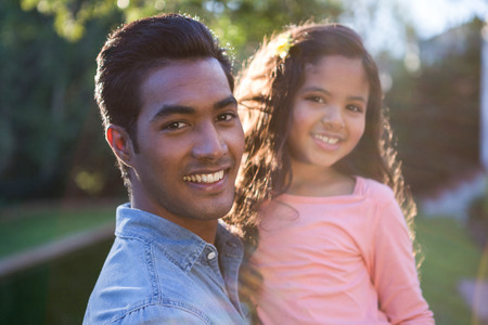 Portrait of father carrying daughter in his arms in the gardenの写真素材