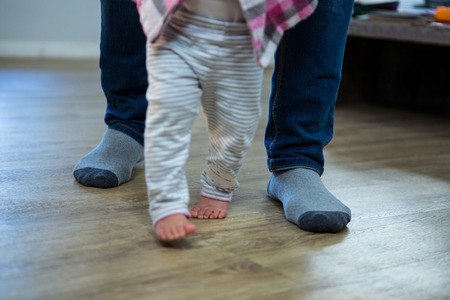 Father teaching a baby to walk at homeの写真素材