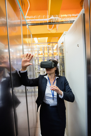 Technician using visual reality headset in hallway of server room