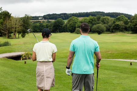 Rear view of couple standing on a golf courseの写真素材