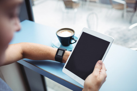 Businesswoman using digital tablet while having coffee in officeの写真素材